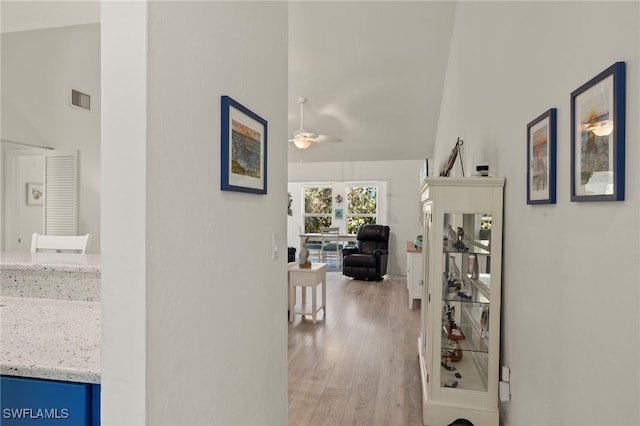 hallway with light hardwood / wood-style flooring and high vaulted ceiling