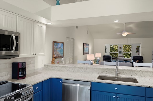 kitchen featuring sink, stainless steel appliances, light stone countertops, decorative backsplash, and vaulted ceiling