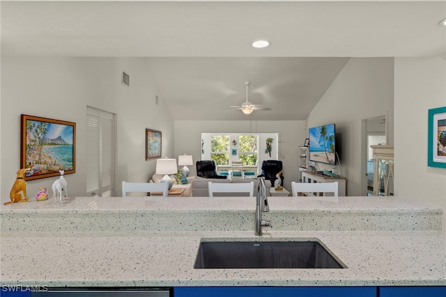 kitchen with ceiling fan, lofted ceiling, sink, and light stone counters