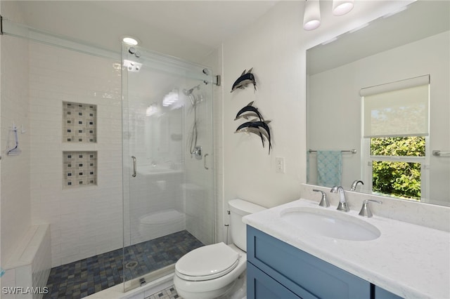 bathroom with a shower with door, vanity, and toilet