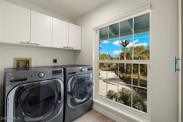 laundry room featuring cabinets, light hardwood / wood-style floors, and washer and dryer