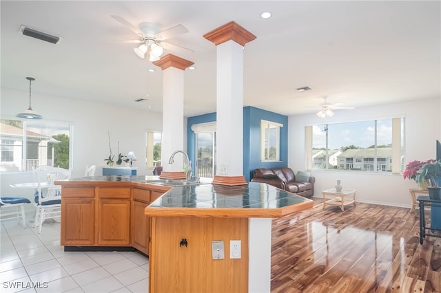 kitchen featuring plenty of natural light, light wood-type flooring, decorative light fixtures, and sink