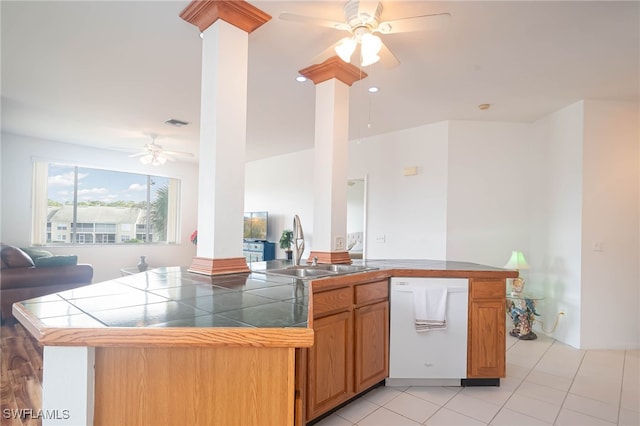 kitchen with dishwasher, sink, ornate columns, tile counters, and light tile patterned flooring