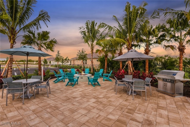 patio terrace at dusk with grilling area and a fire pit