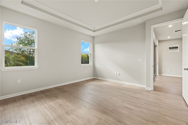 unfurnished room with light hardwood / wood-style floors and a raised ceiling