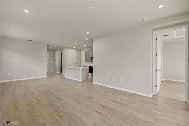 unfurnished living room with sink and light wood-type flooring