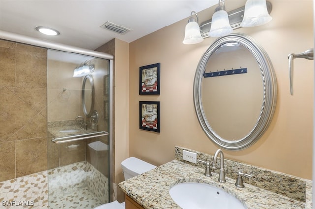 bathroom featuring vanity, toilet, and a shower with door