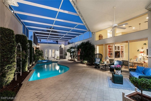 view of pool featuring glass enclosure, a patio, a ceiling fan, and an outdoor living space