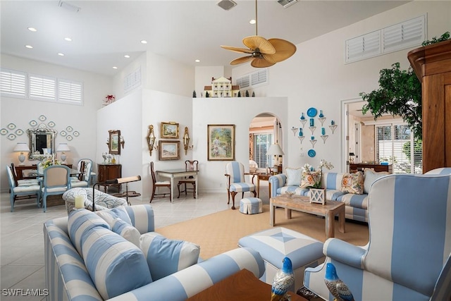 living room featuring ceiling fan, light tile patterned floors, recessed lighting, a high ceiling, and arched walkways