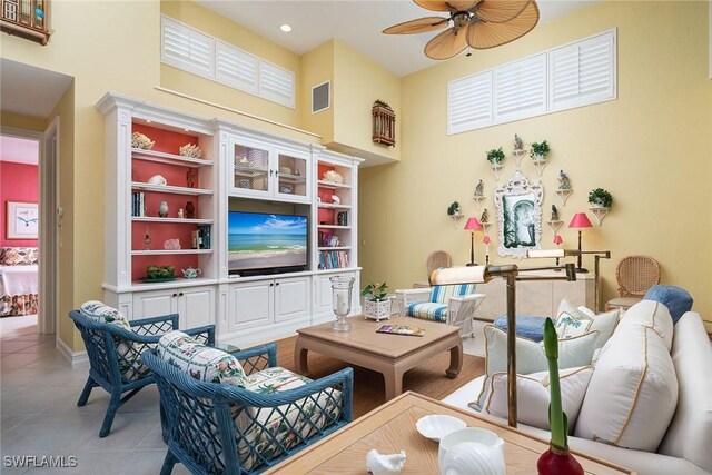 tiled living room with ceiling fan and a towering ceiling