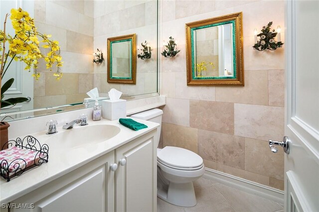 bathroom with tile patterned floors, vanity, toilet, and tile walls