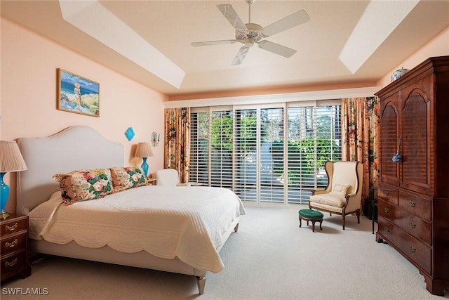 bedroom with access to outside, ceiling fan, a tray ceiling, and carpet floors