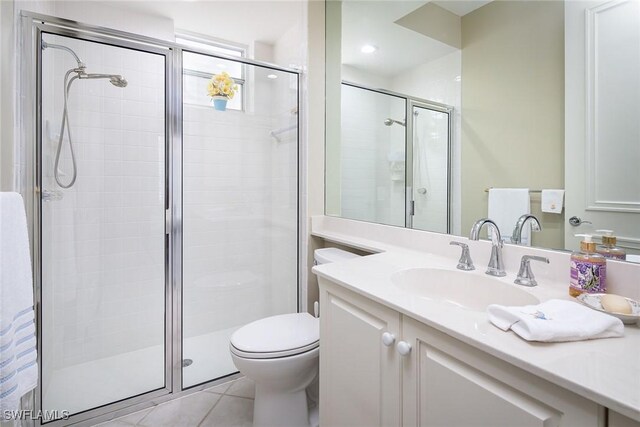 bathroom featuring toilet, a stall shower, vanity, and tile patterned flooring