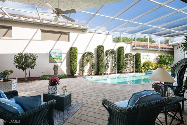 view of swimming pool featuring outdoor lounge area, glass enclosure, ceiling fan, and a patio area