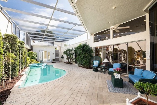 view of pool with a pool with connected hot tub, a patio, glass enclosure, outdoor lounge area, and ceiling fan