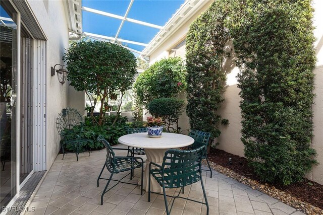 view of patio with glass enclosure and outdoor dining space