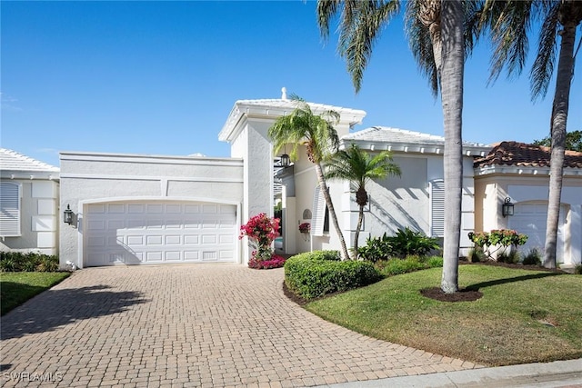 view of front of house with stucco siding, decorative driveway, a front lawn, and an attached garage