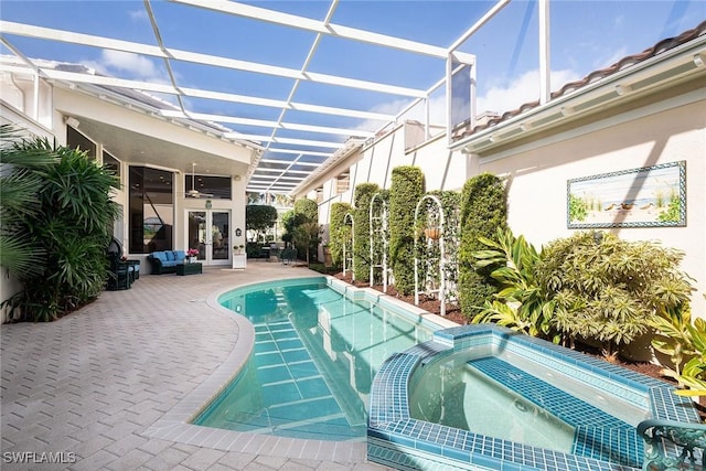 view of pool with french doors, a pool with connected hot tub, glass enclosure, and a patio area