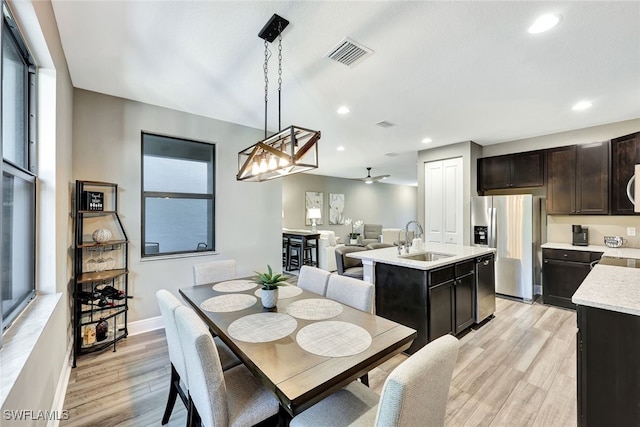 dining space featuring ceiling fan, light wood-type flooring, sink, and a wealth of natural light