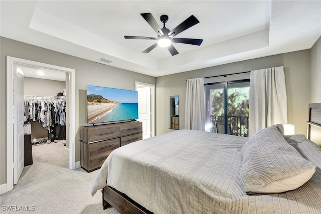 bedroom with light carpet, a tray ceiling, and ceiling fan