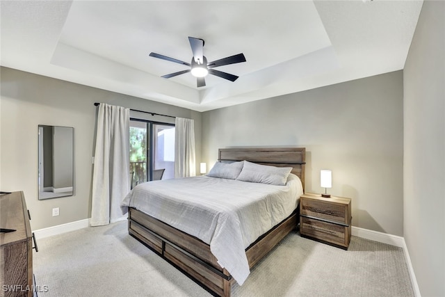 carpeted bedroom featuring access to exterior, a raised ceiling, and ceiling fan