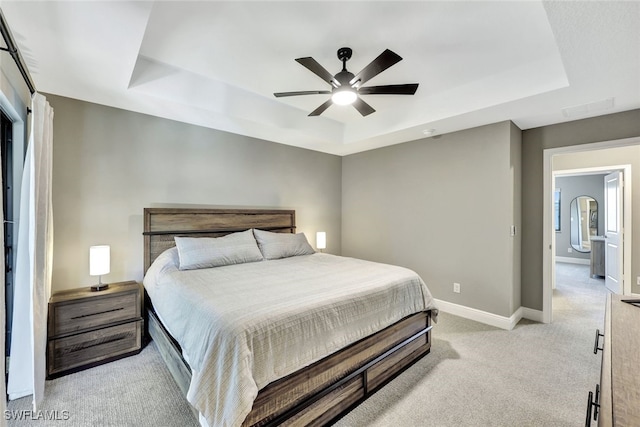 carpeted bedroom featuring ceiling fan and a tray ceiling