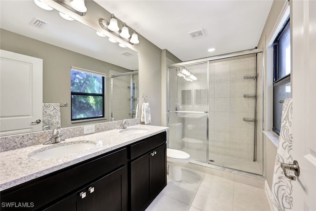 bathroom featuring tile patterned flooring, vanity, a shower with shower door, and toilet