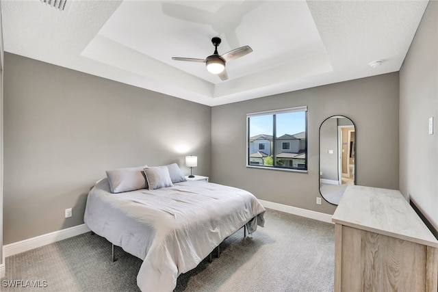 carpeted bedroom featuring ceiling fan and a tray ceiling