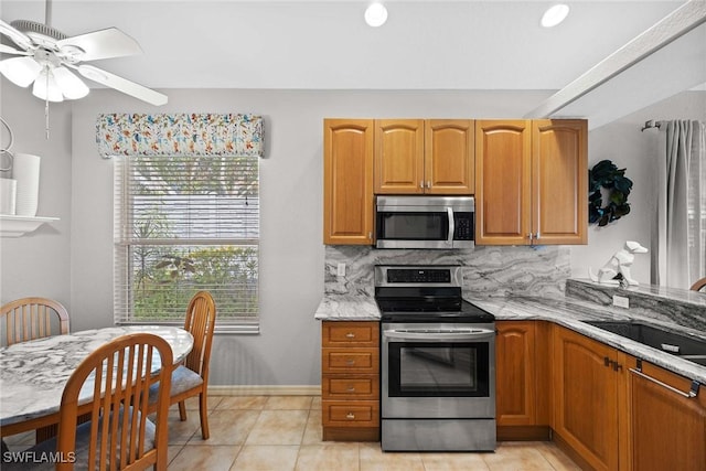 kitchen featuring appliances with stainless steel finishes, light stone counters, light tile patterned floors, and sink