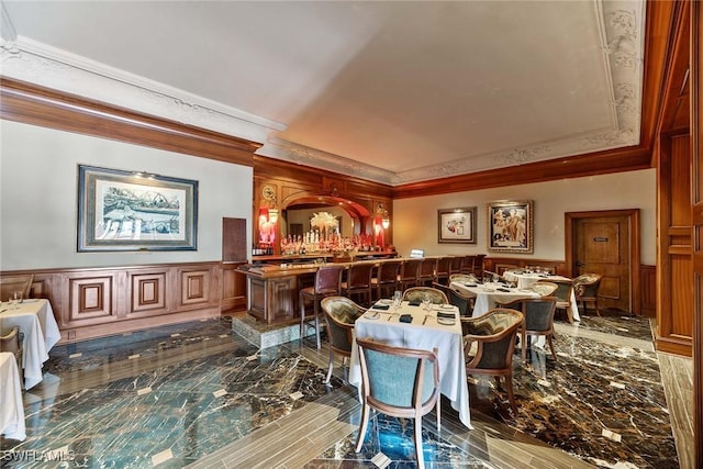 interior space featuring bar, ornamental molding, and wood walls