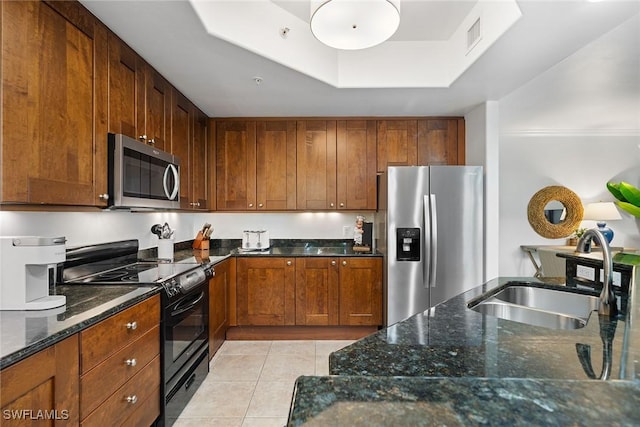 kitchen featuring sink, light tile patterned flooring, dark stone counters, and appliances with stainless steel finishes