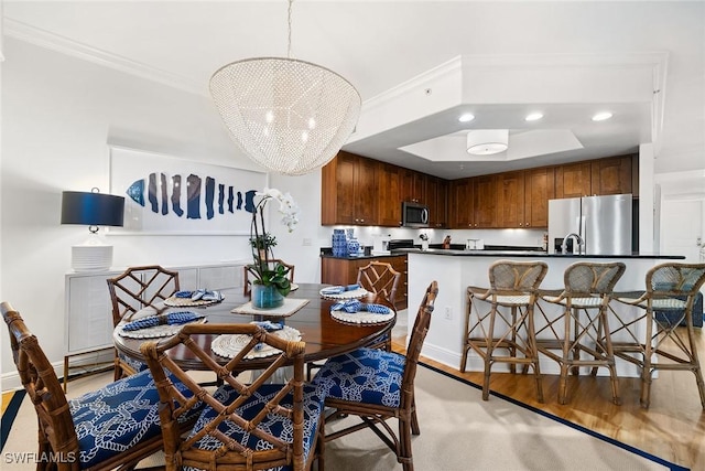 dining area with light hardwood / wood-style floors, an inviting chandelier, and crown molding