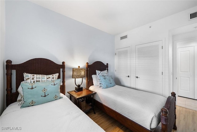 bedroom with wood-type flooring and multiple closets