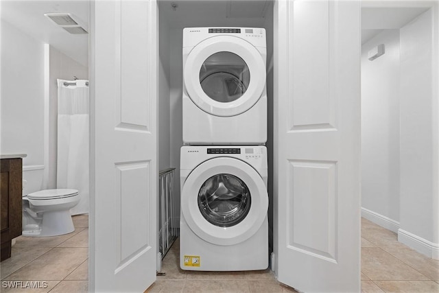 washroom with light tile patterned floors and stacked washer and clothes dryer