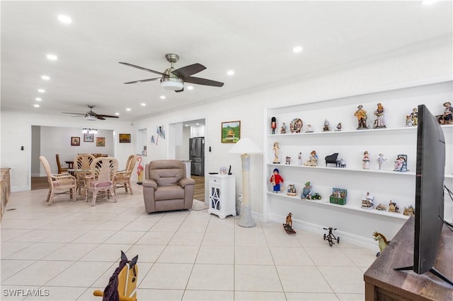 living room with light tile patterned flooring, ceiling fan, crown molding, and built in features