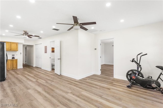 exercise area with ceiling fan and light hardwood / wood-style flooring