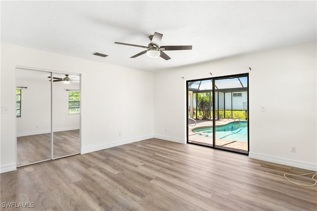 unfurnished room featuring ceiling fan, a wealth of natural light, light hardwood / wood-style floors, and access to outside