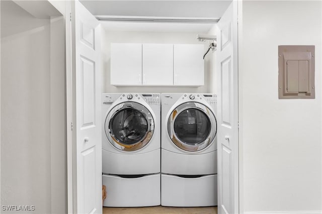 washroom featuring cabinets, washer and dryer, and electric panel