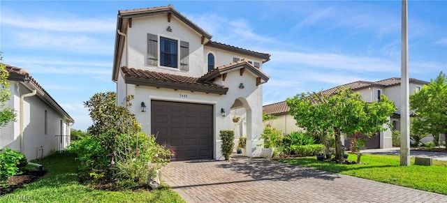 mediterranean / spanish house featuring a front yard and a garage