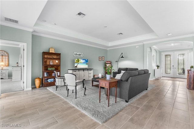 living room featuring french doors, a tray ceiling, and ornamental molding