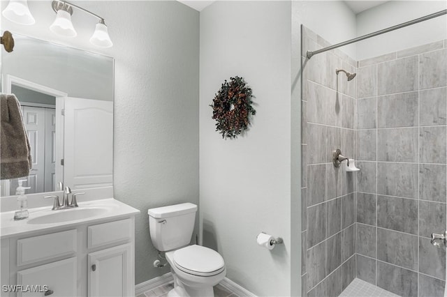 bathroom with vanity, toilet, and a tile shower