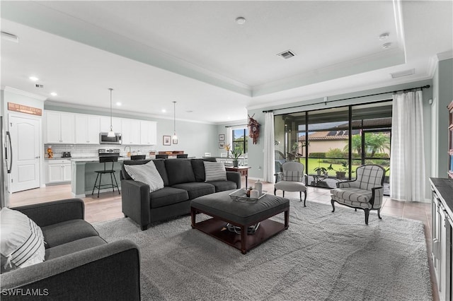 living room with crown molding, a wealth of natural light, and a tray ceiling