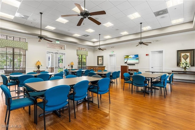 dining room with ceiling fan, french doors, wood-type flooring, and a drop ceiling