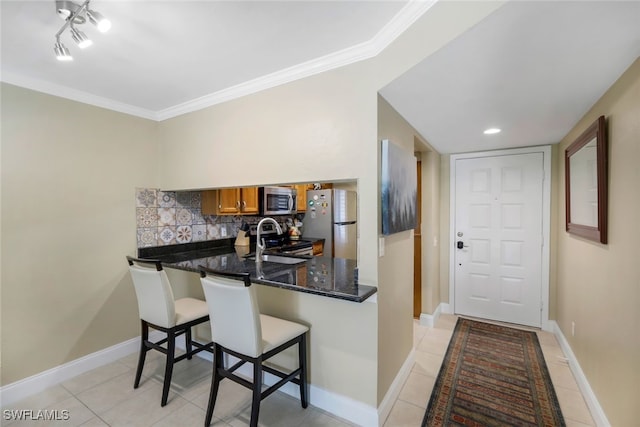 kitchen with brown cabinets, tasteful backsplash, stainless steel appliances, a peninsula, and baseboards