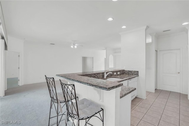 kitchen with a kitchen bar, sink, white cabinetry, ornamental molding, and kitchen peninsula