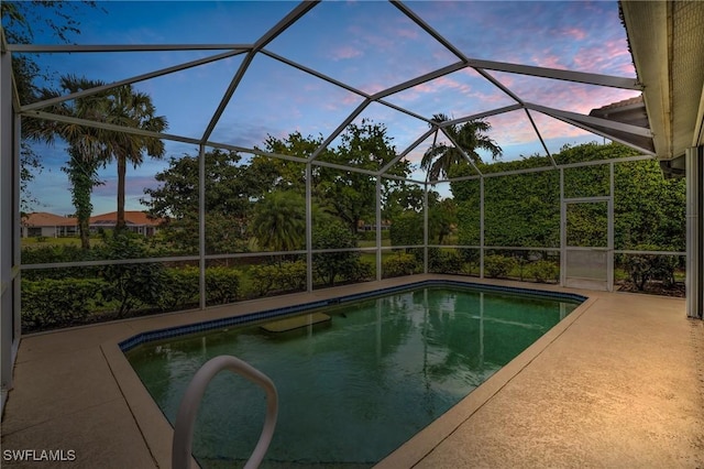 pool at dusk with a patio and a lanai