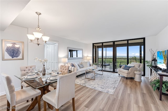 dining room with a wall of windows, a chandelier, and light hardwood / wood-style flooring