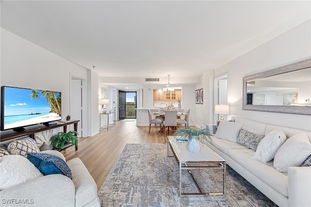 living room with an inviting chandelier and light hardwood / wood-style floors