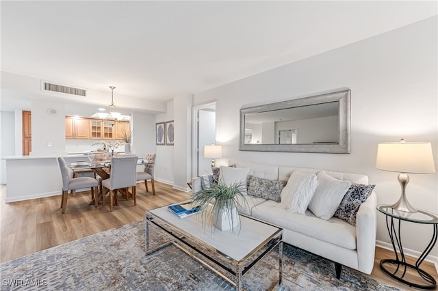 living room with an inviting chandelier and light wood-type flooring