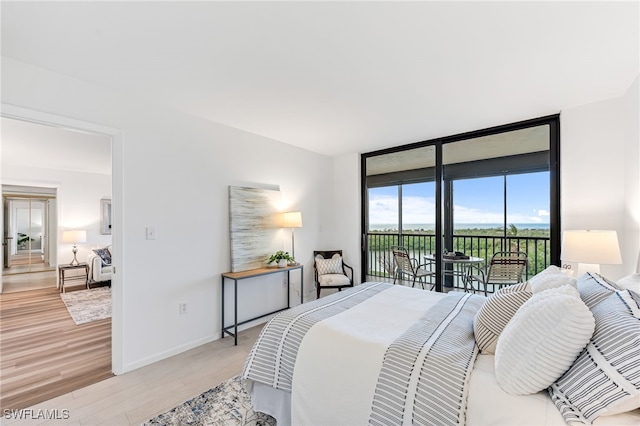 bedroom with floor to ceiling windows, access to exterior, and light wood-type flooring